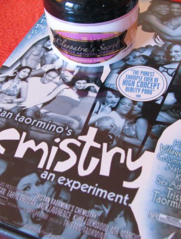 Chemistry Vol. 1 porn DVD by Tristan Taormino, lying on an orange blanket with a container of arousal cream on top.