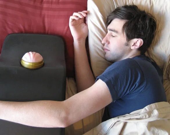 A guy pretending to sleep in bed, with his arm around a Fleshlight mount. Am I supposed to be horrified?