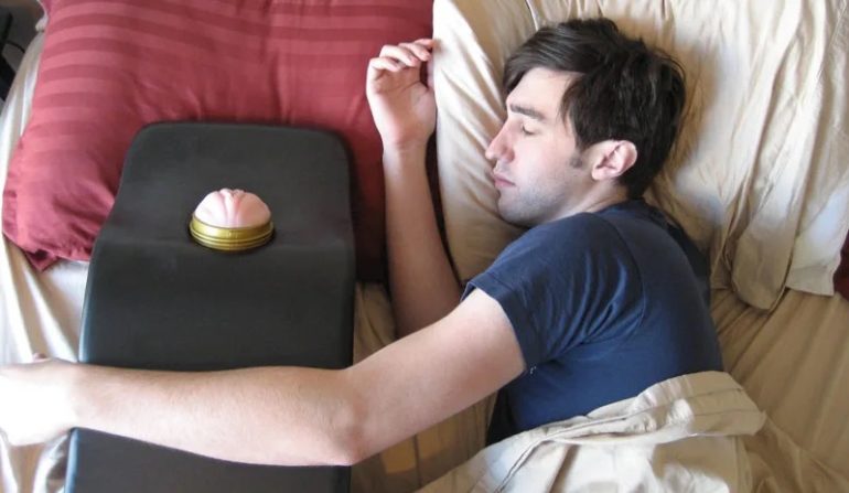 A guy pretending to sleep in bed, with his arm around a Fleshlight mount. Am I supposed to be horrified?