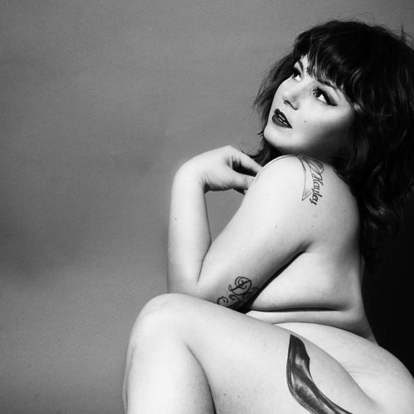 Courtney Trouble, nude, in a black and white shot showing off their high heel tattoo.