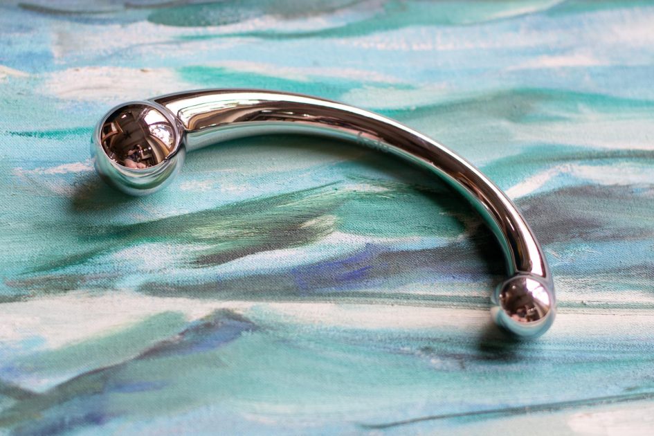 njoy Pure Wand stainless steel G-spot dildo on a painting of the ocean waves.