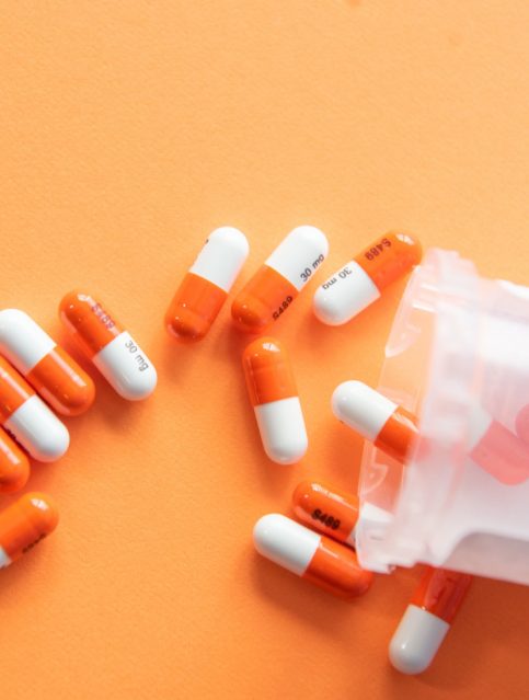 Pills spilled on an orange surface.