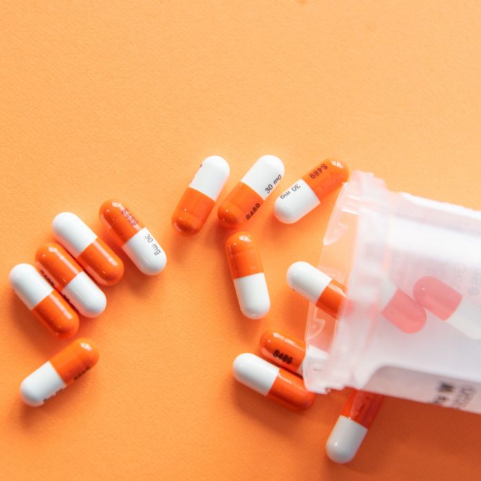 Pills spilled on an orange surface.