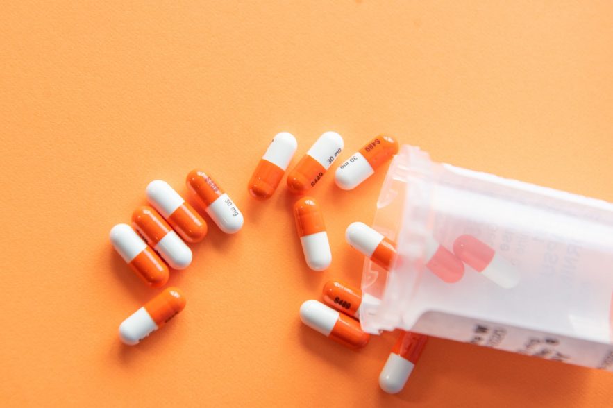 Pills spilled on an orange surface.
