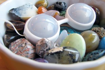 LELO Luna Beads Mini lying in a dish full of colorful stones.