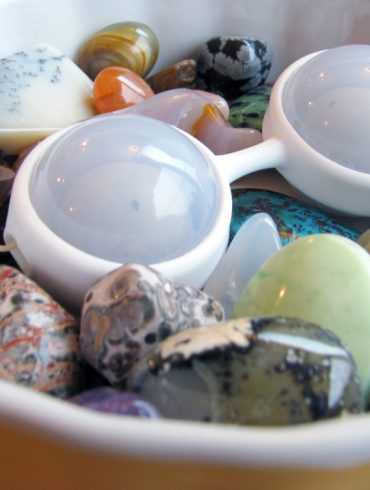 LELO Luna Beads Mini lying in a dish full of colorful stones.
