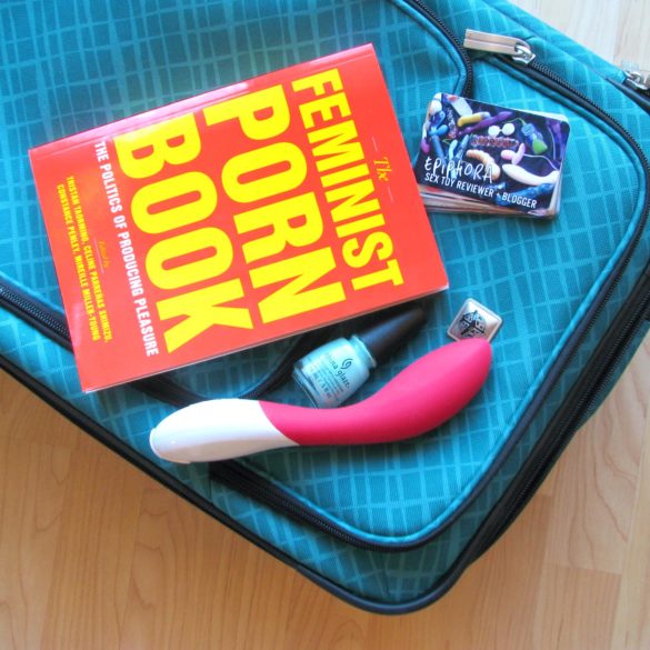 The Feminist Porn Book lying on top of my suitcase, with the LELO Mona 2 and some business cards.