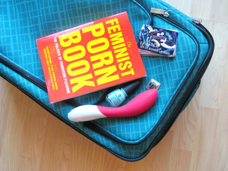 The Feminist Porn Book lying on top of my suitcase, with the LELO Mona 2 and some business cards.