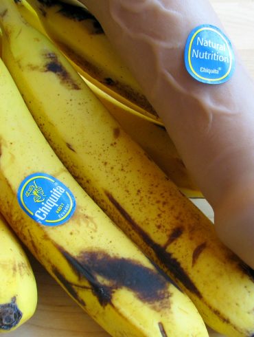 Vixen Creations Buck dildo with a bunch of bananas. Accordingly, the dildo has a Chiquita sticker on it that says NATURAL NUTRITION.