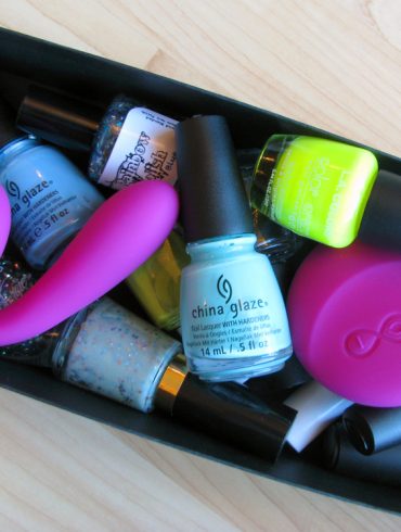 LELO Ida vibrator in a box of various nail polishes.