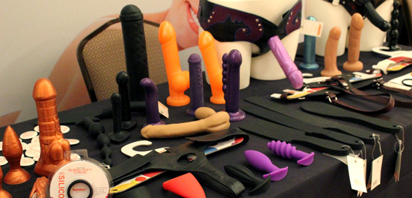 Tantus table at CatalystCon West, covered in dildos and butt plugs.