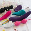 Colorful vibrators and kegel balls surrounded by iridescent curly ribbons.