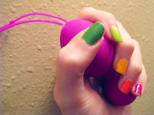 Me grasping the Jopen VR1 kegel balls, with rainbow-painted nails.