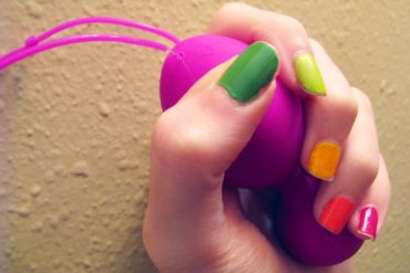 Me grasping the Jopen VR1 kegel balls, with rainbow-painted nails.