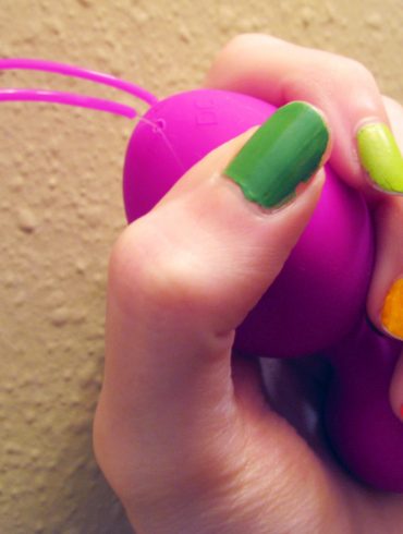 Me grasping the Jopen VR1 kegel balls, with rainbow-painted nails.