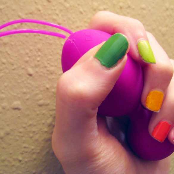 Me grasping the Jopen VR1 kegel balls, with rainbow-painted nails.