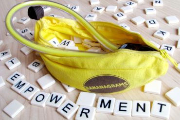 Magic Banana kegel exerciser and dildo, surrounded by plastic letters from the Bananagrams game spelling out "EMPOWERMENT."