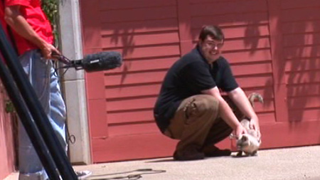 Dude shamelessly petting a cat in the Behind the Scenes of Kayden Exposed.