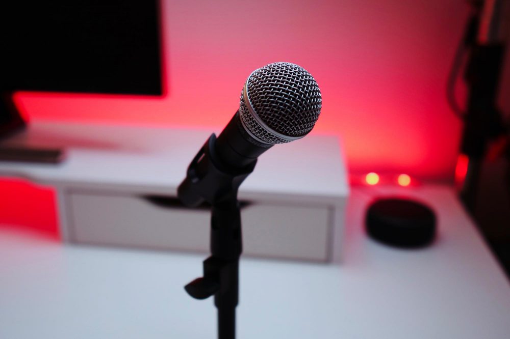 Microphone in front of a computer, with some pretty red lighting in the back.