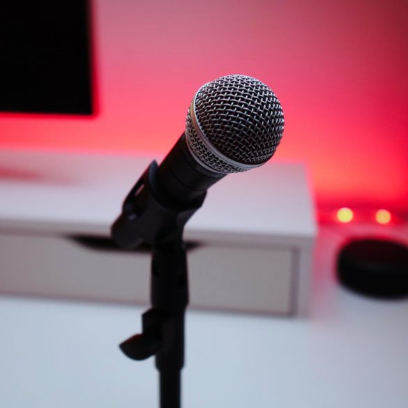 Microphone in front of a computer, with some pretty red lighting in the back.