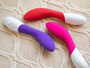 LELO Mona 2 in all three colors (red, purple, pink AKA cerise) on a graduated wooden shelf.