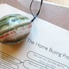 Stone egg lying on top of a brochure for "the home buying process."