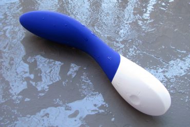 LELO Mona Wave rechargeable G-spot vibrator on a rainy cement surface.