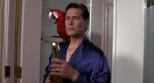 Hugo Posh (James Remar) being majestic in The Girl Next Door, holding a porn trophy, with a Macaw perched on his shoulder.