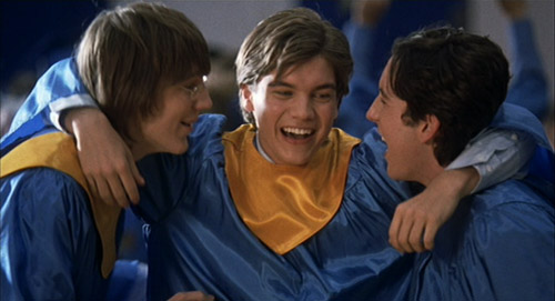 Klitzy (Paul Dano), Matthew (Emile Hirsch), and Eli (Chris Marquette) hugging in their graduation gowns in The Girl Next Door.