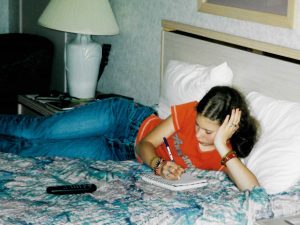 Me in a motel in 2002, on the bed writing in my journal.
