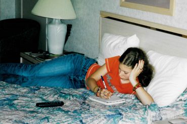 Me in a motel in 2002, on the bed writing in my journal.