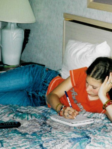 Me in a motel in 2002, on the bed writing in my journal.
