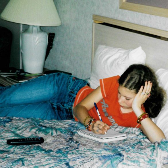 Me in a motel in 2002, on the bed writing in my journal.