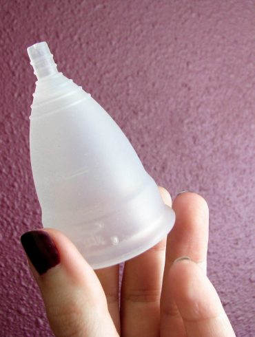 Me holding the Diva Cup silicone menstrual cup, with appropriately blood-colored polish on my fingernails.