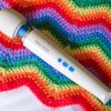 Hitachi Magic Wand Rechargeable vibrator on a zig-zag-patterned rainbow crocheted blanket.