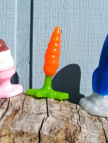 Hole Punch Toys Ass Cram Cone, Plugs Bunny, and Crotch Rocket standing on a wood pile in front of a pale blue house.