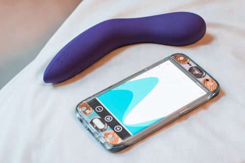 We-Vibe Rave on a bed with a phone showing the We-Connect app.