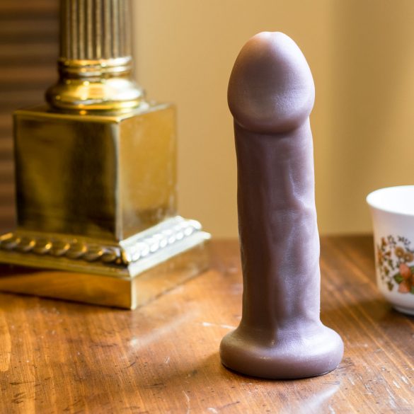 New York Toy Collective Carter silicone dildo on a nightstand, next to a golden lamp base and a floral tea cup.