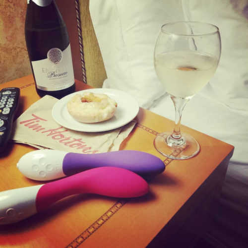 Two LELO Mona 2s on my nightstand with wine and donut.