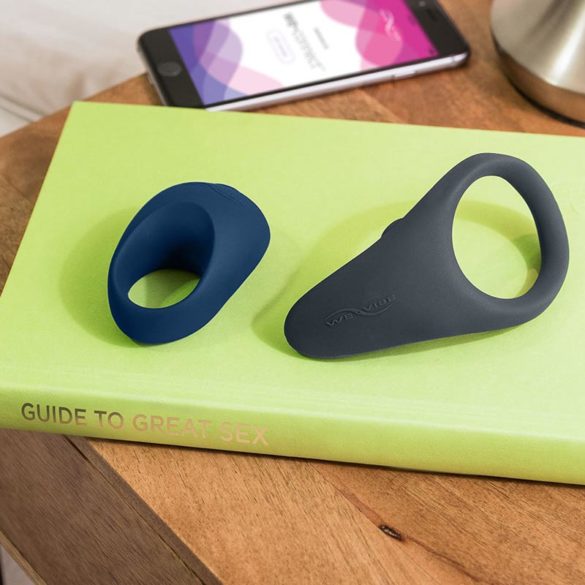 We-Vibe Pivot and Verge cock rings lying on a book on top of a nightstand.