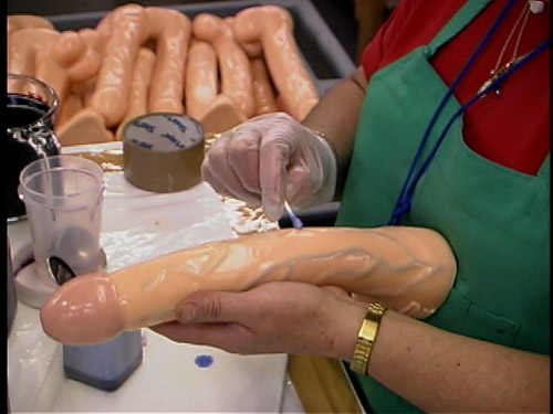 A factory worker painting blue veins on a dildo at Topco.