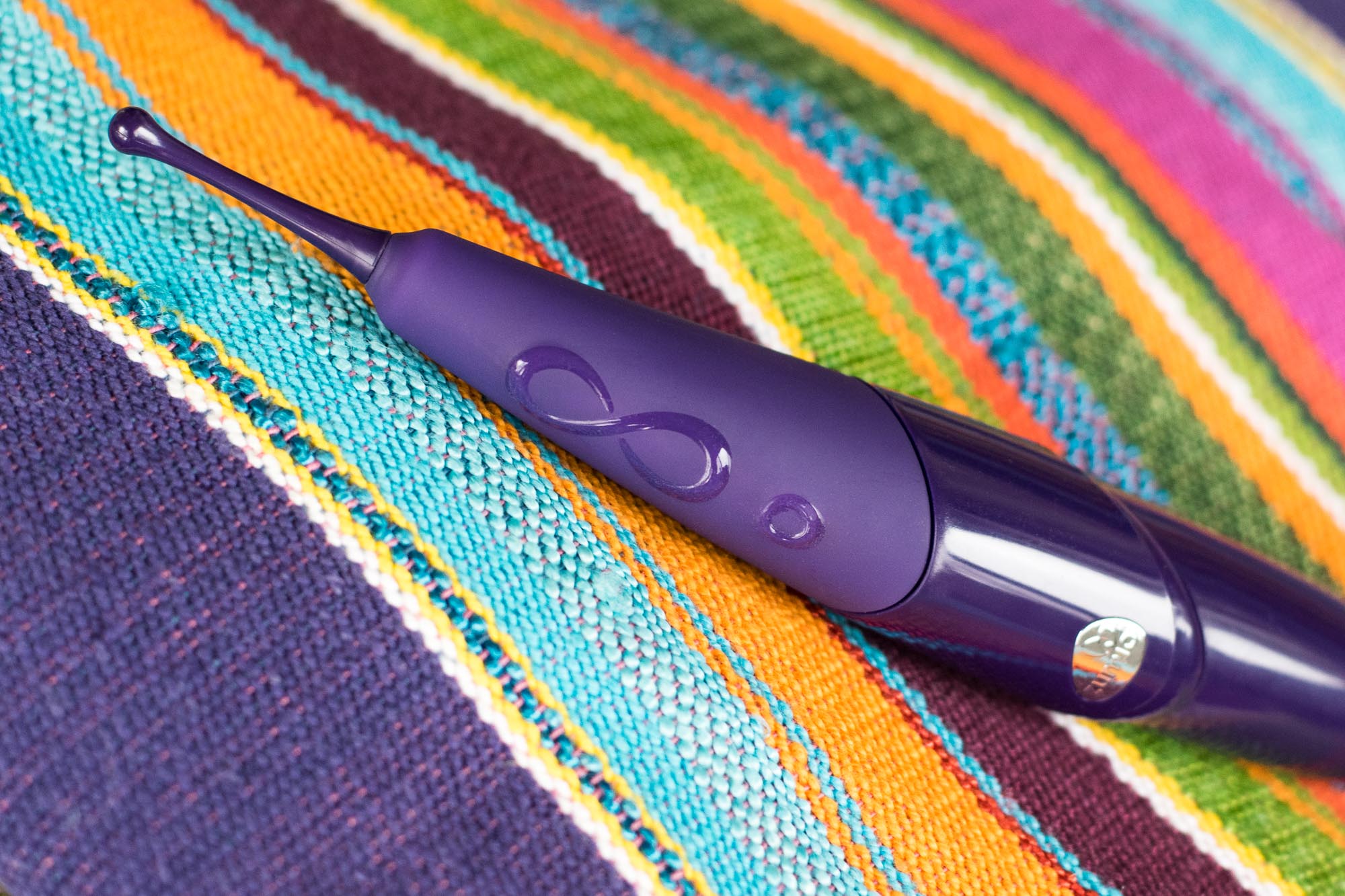 Zumio X rechargeable clitoral vibrator, on a colorful striped blanket.