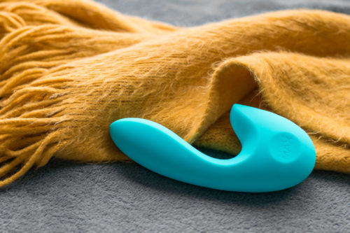 SenseMax SenseVibe rechargeable dual vibrator next to a burnt yellow fuzzy scarf.