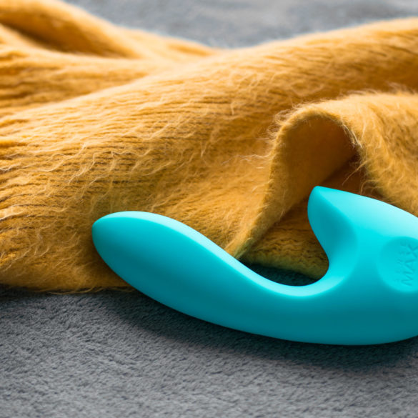 SenseMax SenseVibe rechargeable dual vibrator next to a burnt yellow fuzzy scarf.