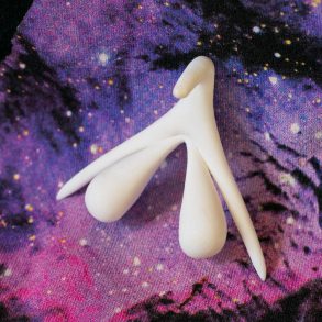 3D-printed clitoris organ, showing the entire external and internal structure, on a galaxy backdrop.