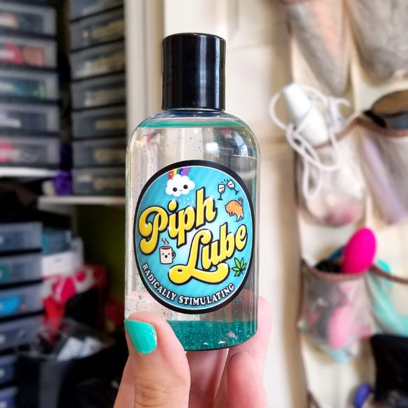 Piph Lube, with the glitter settled at the bottom, in front of my sex toy closet.