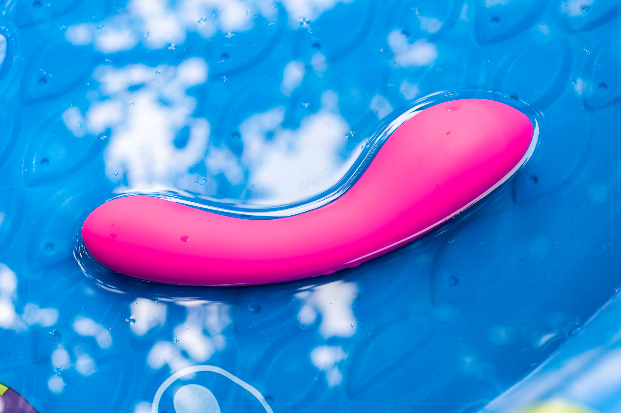 BMS Factory Swan Wand vibrator and its reflection, in shallow water in a kiddie pool.