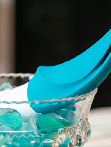 Fun Factory Volta rechargeable vibrator hanging out in a glass bowl of sea glass.