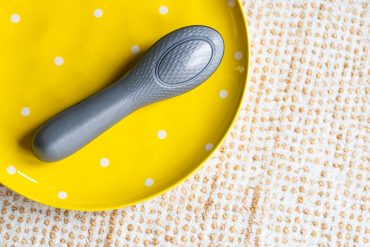 Hot Octopuss Queen Bee oscillating rechargeable vibrator on a yellow polka dot plate.