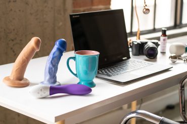 A sex blogger's desk: dildos, coffee, laptop, etc.